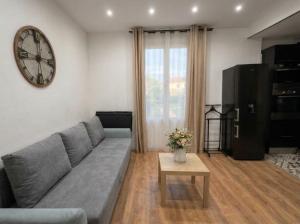 a living room with a couch and a clock on the wall at F2 cosy et calme 15 min de Paris, commerces à pied in Alfortville