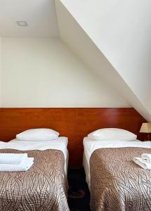 two beds in a hotel room with a attic at Akme APARTMENTS & ROOMS & FREE PARKING in Gdańsk