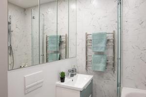 a white bathroom with a sink and a mirror at Cozy Apartment Mazeikiai in Mažeikiai