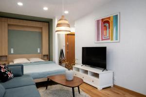 a bedroom with a bed and a tv and a couch at Cozy Apartment Mazeikiai in Mažeikiai