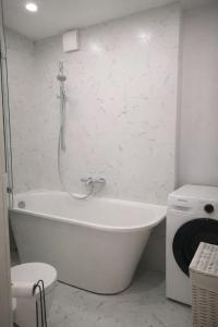 a white bath tub in a bathroom with a shower at Cozy Apartment Mazeikiai in Mažeikiai