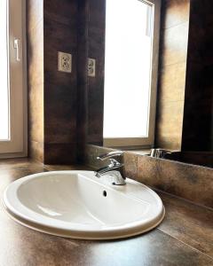 a white sink in a bathroom with a mirror at Akme APARTMENTS & ROOMS & FREE PARKING in Gdańsk