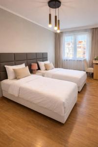 two beds in a hotel room with white sheets at Plac 14- Apartamenty i pokoje w centrum in Świnoujście