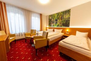 a hotel room with two beds and a table and chairs at Hotel Zum Goldenen Löwen in Peitz +32 photos