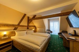 a hotel room with a bed and a flat screen tv at Hotel Zum Goldenen Löwen in Peitz