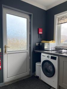 a kitchen with a washing machine and a window at The Homer in Kilmuir