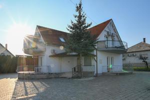 a white house with a tree in front of it at Klassz Apartmanház in Balatonfüred