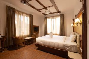 a hotel room with a bed and a desk and window at Welbeck by The Beehives in Ooty