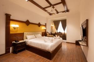 a bedroom with a large bed and a television at Welbeck by The Beehives in Ooty