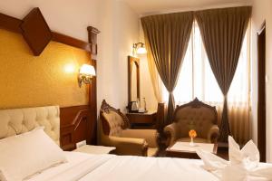 a hotel room with a bed and a chair and a window at Welbeck by The Beehives in Ooty