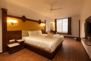 a hotel room with a bed and a flat screen tv at Welbeck by The Beehives in Ooty