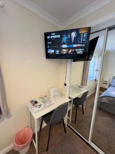 a room with a table and a tv on the wall at Comfortable double room with own bathroom in Inshes