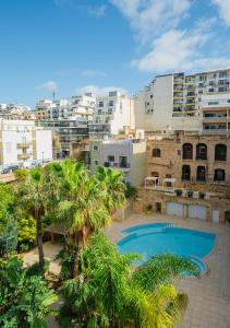 an overhead view of a swimming pool with palm trees and buildings at Maritim Antonine Hotel & Spa in Mellieħa