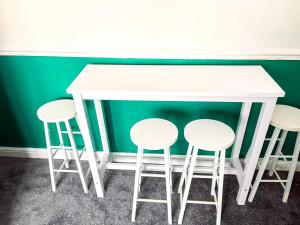 a white table and four stools against a green wall at New Hampton Units in Wolverhampton