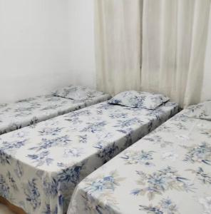 three beds in a room with blue and white sheets at Casa aconchego in São Carlos +3 photos