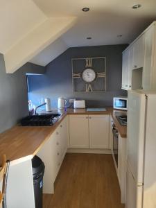 a kitchen with white cabinets and a clock on the wall at Three horse shoes in Durham +1 photo