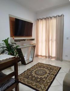a living room with a flat screen tv and a table at Casa aconchego in São Carlos