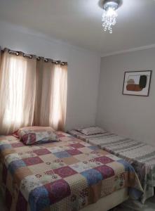 a bedroom with a bed with a quilt on it at Casa aconchego in São Carlos