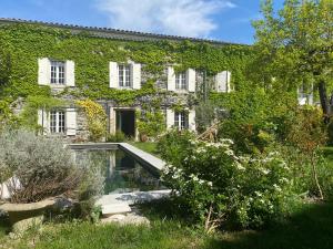 an ivy covered building with a swimming pool at Le Rucher des Arts in Alba-la-Romaine