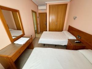 a small room with two beds and a mirror at Hostal Fuentes in Labajos