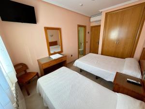 a hotel room with two beds and a mirror at Hostal Fuentes in Labajos