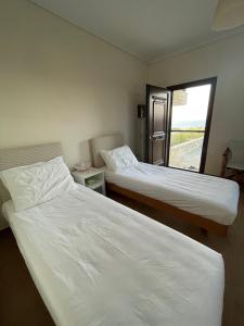 two beds in a room with a window at Dream House in Nea Roda