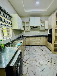 a kitchen with white cabinets and a marble floor at Polo Apartments Lekki in Lekki