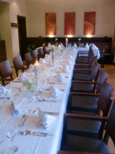 una mesa larga con platos, vasos y velas en Hotel Pfeffermühle en Borchen