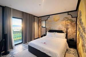 a bedroom with a large bed with a painting on the wall at Dragon King Hotel Nghệ An in Cửa Lô