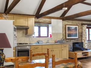 a kitchen with wooden cabinets and a table with chairs at The Hayloft - Uk50027 in Liskeard
