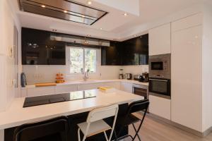 a kitchen with white cabinets and a large island with chairs at Villa Blanca Santa Eulalia in Santa Eularia des Riu +31 photos