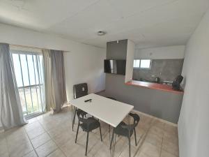 a dining room with a white table and chairs at Depto guemez1 in General Roca