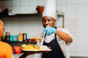 a chef eating a plate of food with a spoon at Kampala Kolping Hotel in Kampala