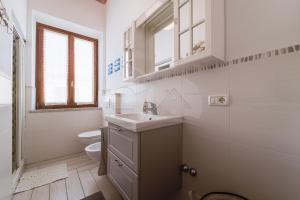 a white bathroom with a sink and a toilet at Appartamento Zoe - Goelba in Marina di Campo