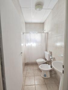 a white bathroom with a toilet and a sink at Depto guemez1 in General Roca