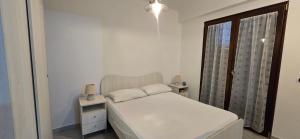 a small white bedroom with a bed and a window at La Casetta Nuova struttura in Palinuro