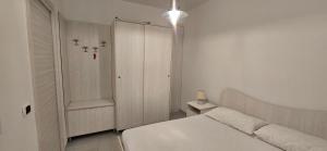 a white bedroom with a bed and a cabinet at La Casetta Nuova struttura in Palinuro