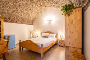 a bedroom with a wooden bed and a stone wall at Antica corte in Zogno