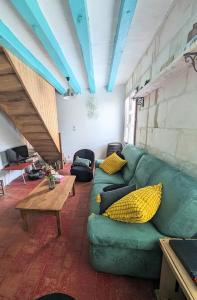 a living room with a green couch and a table at La rose d'Alfred in Chédigny