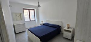 a white bedroom with a blue bed and a window at La Casetta Mare in Palinuro