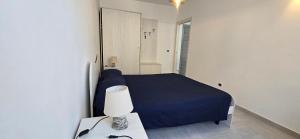 a bedroom with a blue bed and a table with a lamp at La Casetta Mare in Palinuro +4 photos