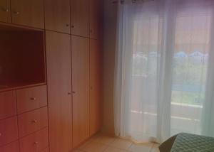 a bedroom with a large window with white curtains at Στης Χαράς in Porto Heli