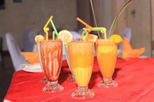 three glasses of orange juice on a table at HOIMA KOLPING HOTEL in Hoima