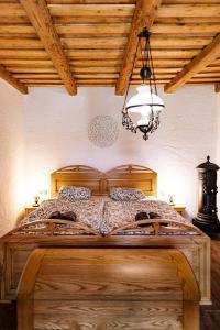a bedroom with a large wooden bed with a chandelier at 100éves Vendégház in Hárskút