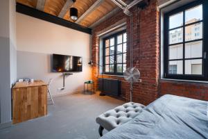 a room with a brick wall and a bed and a television at ON Rooms Łódź in Łódź