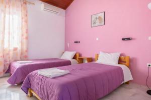 two beds in a room with purple walls at Ionian Breeze Apartments in Kavos