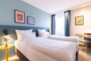 a hotel room with a large bed with white sheets at Hotel Boulevard in Stuttgart
