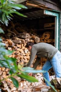a man is leaning over a pile of fire wood at Glass Forest Cabin Holenduif I Privacy I 3BR Quiet in Oostkamp