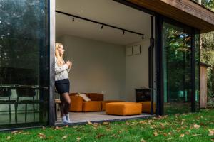 a woman is standing inside of a house at Glass Forest Cabin Holenduif I Privacy I 3BR Quiet in Oostkamp +16 photos
