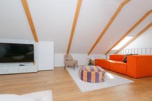 a living room with an orange couch and a tv at The Loft in Sovata